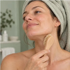 Femme brossant sa mâchoire avec la brosse visage à poils naturels, serviette sur la tête